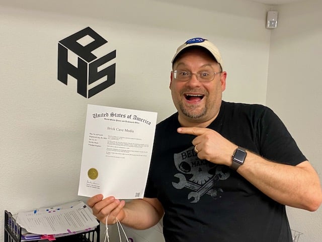 Accelerate staging office environment with enthusiastic man holding a certificate, showcasing success and achievement in a professional workspace.