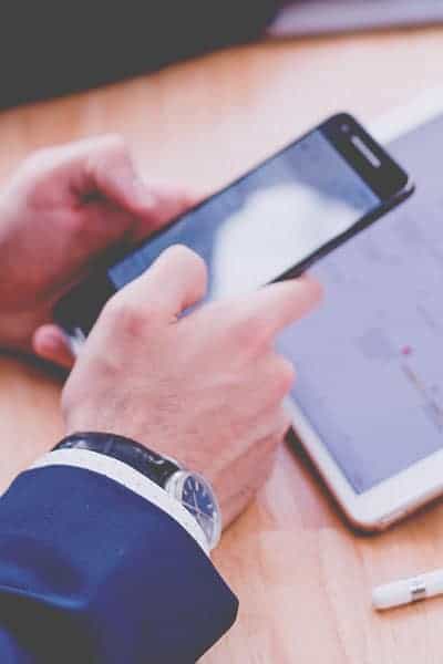 Smartphone and tablet displaying business or financial data on a wooden desk.